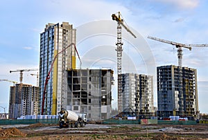 Heavy mixer concrete truck for to be loaded concrete at a construction site. Tower crane lifting a concrete bucket for pouring