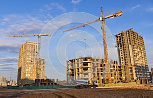 Heavy mixer concrete truck for to be loaded concrete at a construction site. Tower crane lifting a concrete bucket for pouring