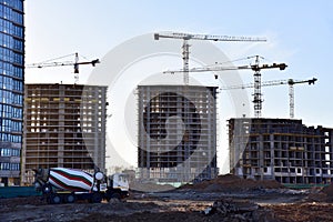 Heavy mixer concrete truck waiting for to be loaded concrete at a construction site. Tower crane lifting a concrete bucket for