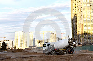 Heavy mixer concrete truck waiting for to be loaded concrete at a construction site. Tower cranes constructing a new residential