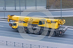 Heavy mobile crane with folding boom construction rides on a city highway