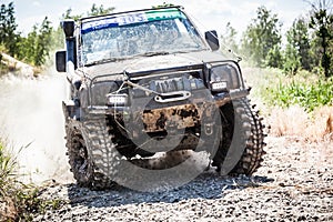 Heavy off-road racing car driving along the dusty road.