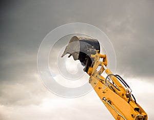 Heavy orange excavator arm reaches the sky