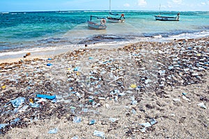 Heavy plastic pollution on the beach of tropical sea. Waste on beach with blue sea background. Cuba