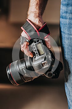 Heavy professional SLR camera with 85 mm portrait telephoto lens - expensive premium photo equipment in the photographer hand