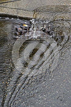 Heavy rain caused flooding in street, water swirling around storm drain