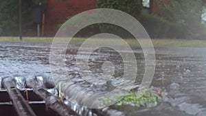 Heavy rain falling on the street and flowing through sewer drain