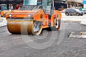 A heavy road vibratory roller compacts fresh asphalt on a new stretch of road