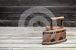 The heavy and rusty old coal iron lies on a wooden surface