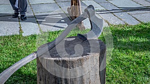Heavy and sharp ax with a wooden handle on a tree stump in the forest