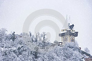 Heavy snow and the famous clock tower on Schlossberg hill, in Graz, Steiermark region, Austria. Selective focus