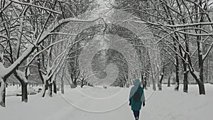 Heavy snowfall in the city. A woman walks along a snowy winter alley.