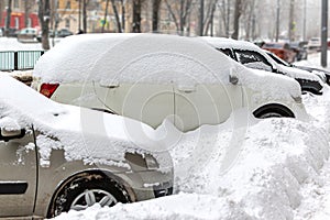 Heavy snowfall cover parked cars on the street of town