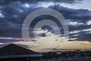 Heavy storm clouds at sunset over town