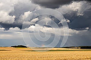 Heavy stormy clouds on sky with rainbow on background