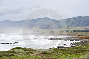 Heavy surf landscape of waves crashing in on rocky shore with mountains behind