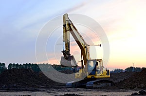 Heavy tracked excavator at a construction site on a background  sunset.