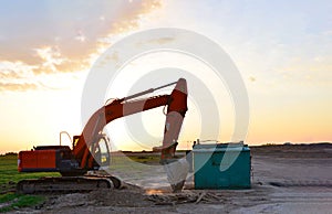 Heavy tracked excavator at a construction site on a background  sunset. Special heavy construction equipment for road construction