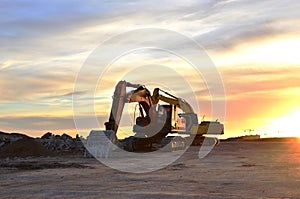 Heavy tracked excavators at a construction site on a background  sunset.