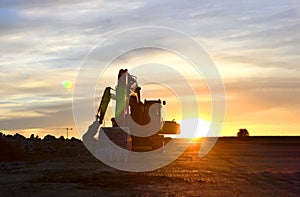 Heavy tracked excavators at a construction site on a background sunset. Special heavy construction equipment for road construction