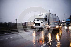Heavy traffic with big rig semi trucks and another cars on highway in rain evening