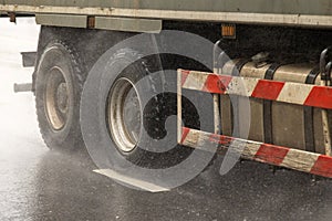 heavy truck moving on a wet road with splashes during the day