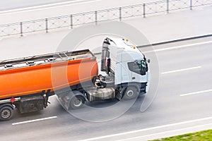 Heavy truck with a tank for flammable liquids rides on the road, close up view