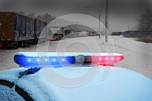 Heavy truck traffic jam on snowy winter ice highway. Police car under snow. Emergency warning flashing red and blue led lights.