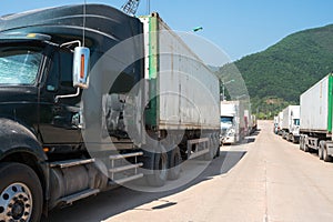 Heavy trucks loaded with goods trailers, parked in waiting area on state border crossing in Vietnam