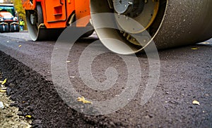 Heavy vibration roller at asphalt pavement works. Road repairing. Selective focus, cropped photo. New asphalt.