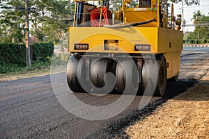 Heavy vibration yellow steamroller or soil compactor working on hot-mix asphalt pavement road