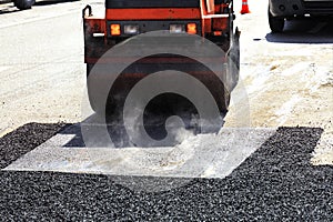 A heavy vibratory road roller compacts asphalt on the repaired stretch of road.