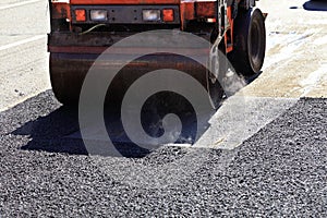 A heavy vibratory road roller compacts asphalt on the repaired stretch of road