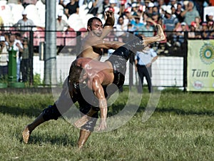 A heavy weight wrestler is tossed into the air by his opponent at the Kirkpinar Turkish Oil Wrestling Festival at Edirne in Turkey