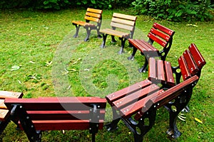 Wood and cast iron garden chairs placed in circle with green grass