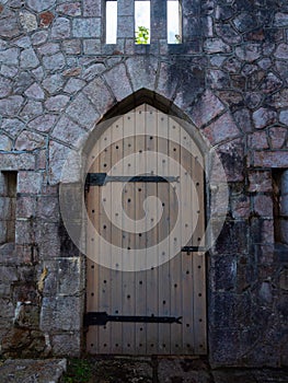 Heavy wooden castle single door with metal bands and studs.  Medieval style set in a stone block wall