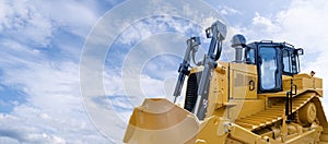 Heavy yellow bulldozer on a background of blue sky.