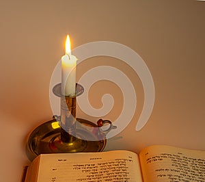 Hebrew bible in the light of a candle on a brass stick