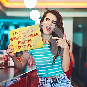Heed this message. an attractive young woman holding up a sign in a retro diner.