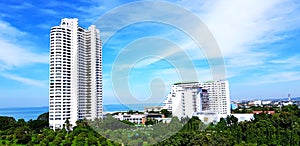 Height white building and small among green tree field with clear blue sky and white cloud background