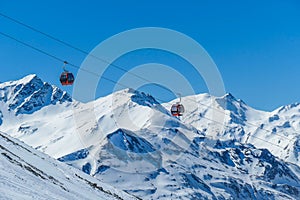 Heiligenblut - Gondola going up and down above the snowy peaks photo