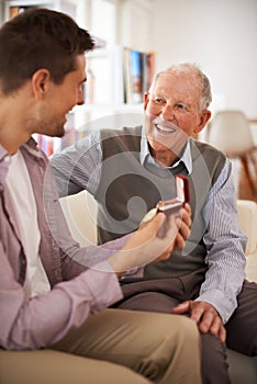 An heirloom of honor. a senior father giving his son a medal as theyre sitting indoors.