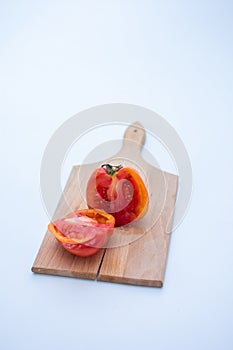 an heirloom tomato cut in half on a small wooden cutting board with a white background