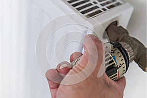 Hand on heater thermostat photo