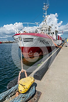 Hel, Poland - 08.01.2021: Vertical wide shot of red and white fishing boat tied to pier on a beautiful sunny summer day