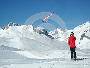 Heli-skiing or mountain rescue helicopter and a skier with copy space for your text