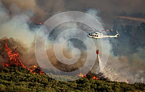 Helicopter with bambi bucket over the fire