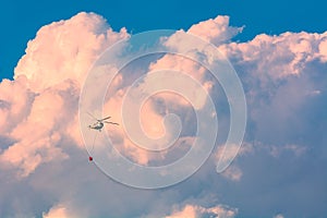 Helicopter with bucket full of water in a sky