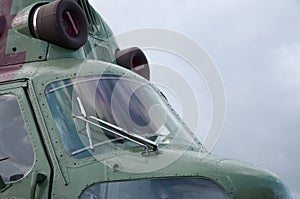 Helicopter cabin fragment close up. Camouflage aircraft fuselage and bulletproof glass