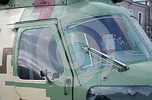 Helicopter cabin fragment close up. Camouflage aircraft fuselage and bulletproof glass